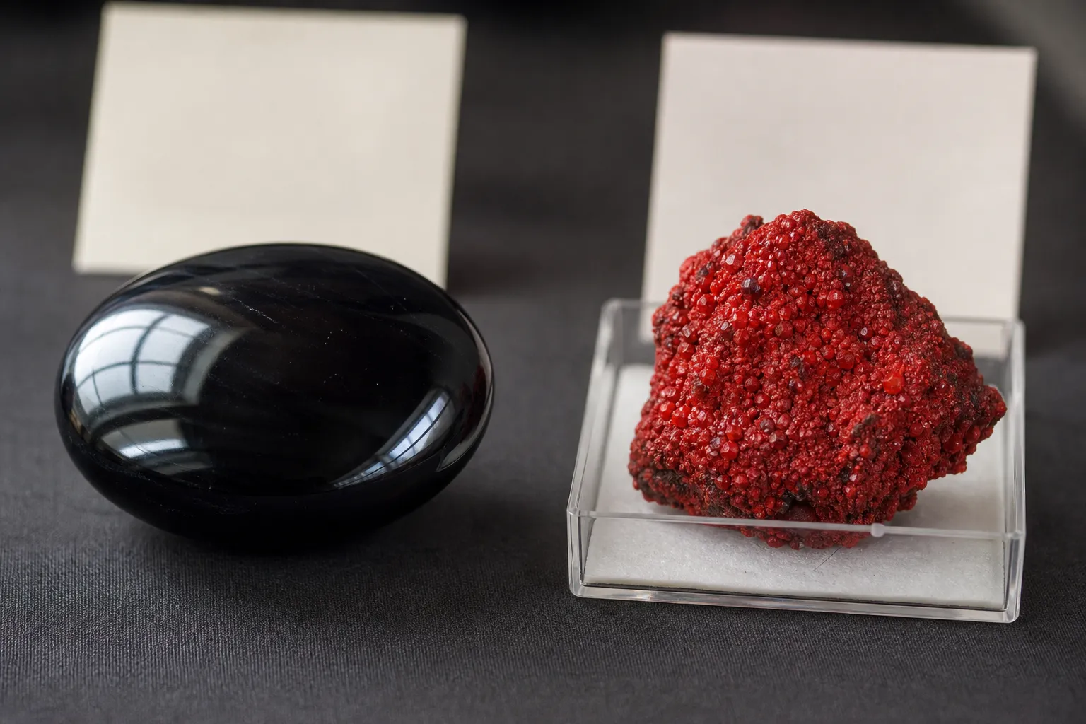 Polished black obsidian beside a red cinnabar specimen for comparing inward protection symbolism with outward vitality symbolism