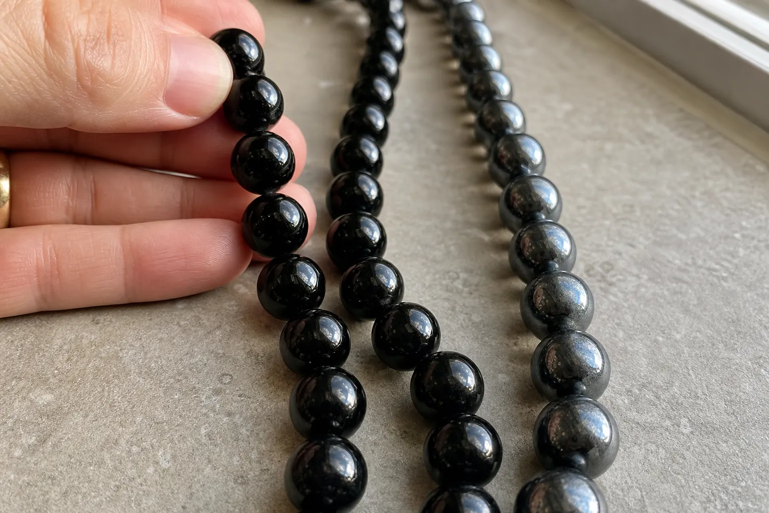 Black obsidian beads and hematite beads compared by glassy black shine and metallic gunmetal shine
