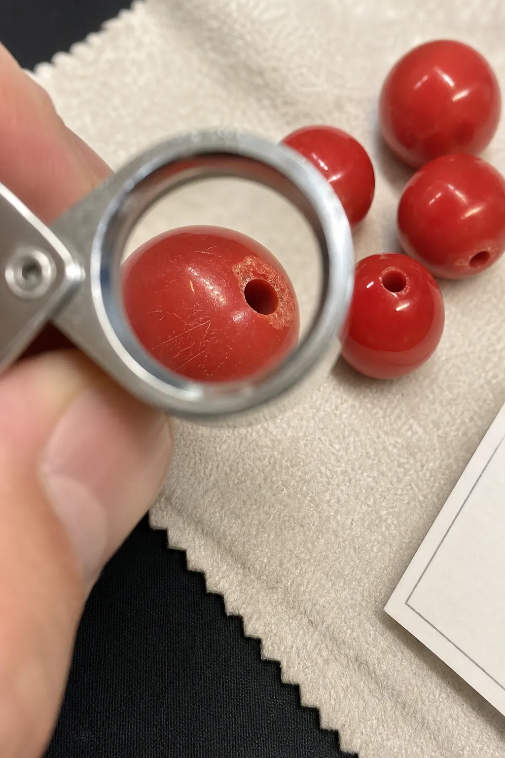 Bright red bead surface checked at drill holes, chipped edges, scratches, and worn spots
