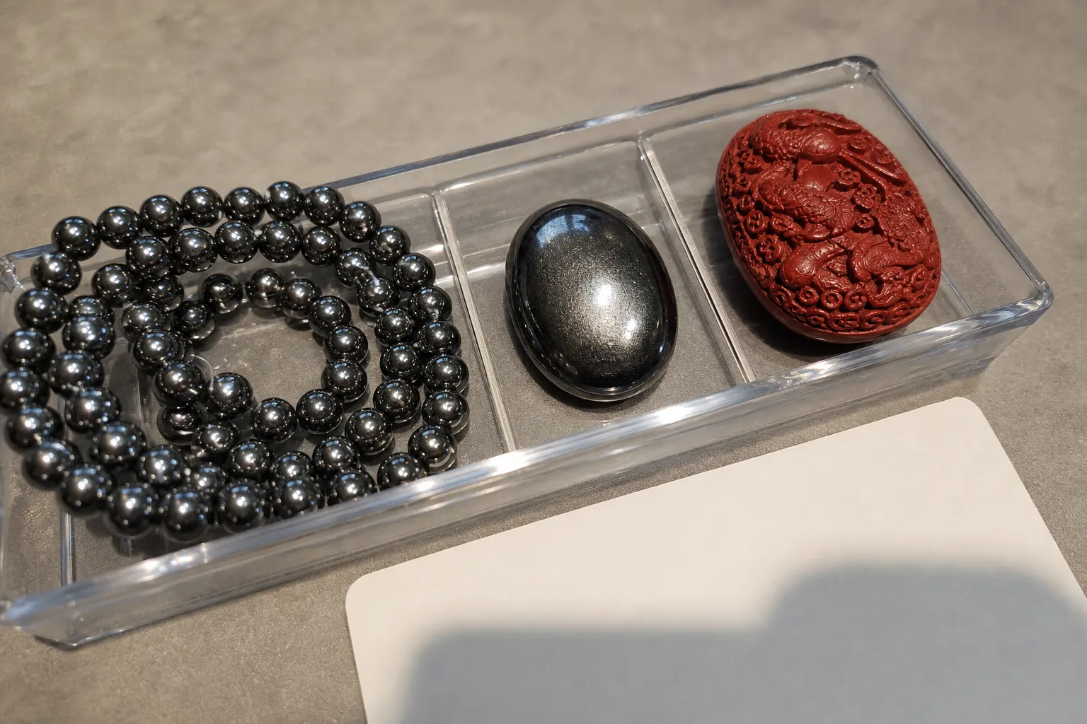 Polished dark hematite-like beads and a red carved object showing how finish can hide color clues