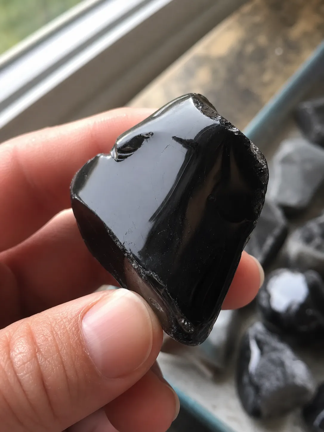 Tumbled obsidian being checked under bright light for chips, thin edges, and uneven polish