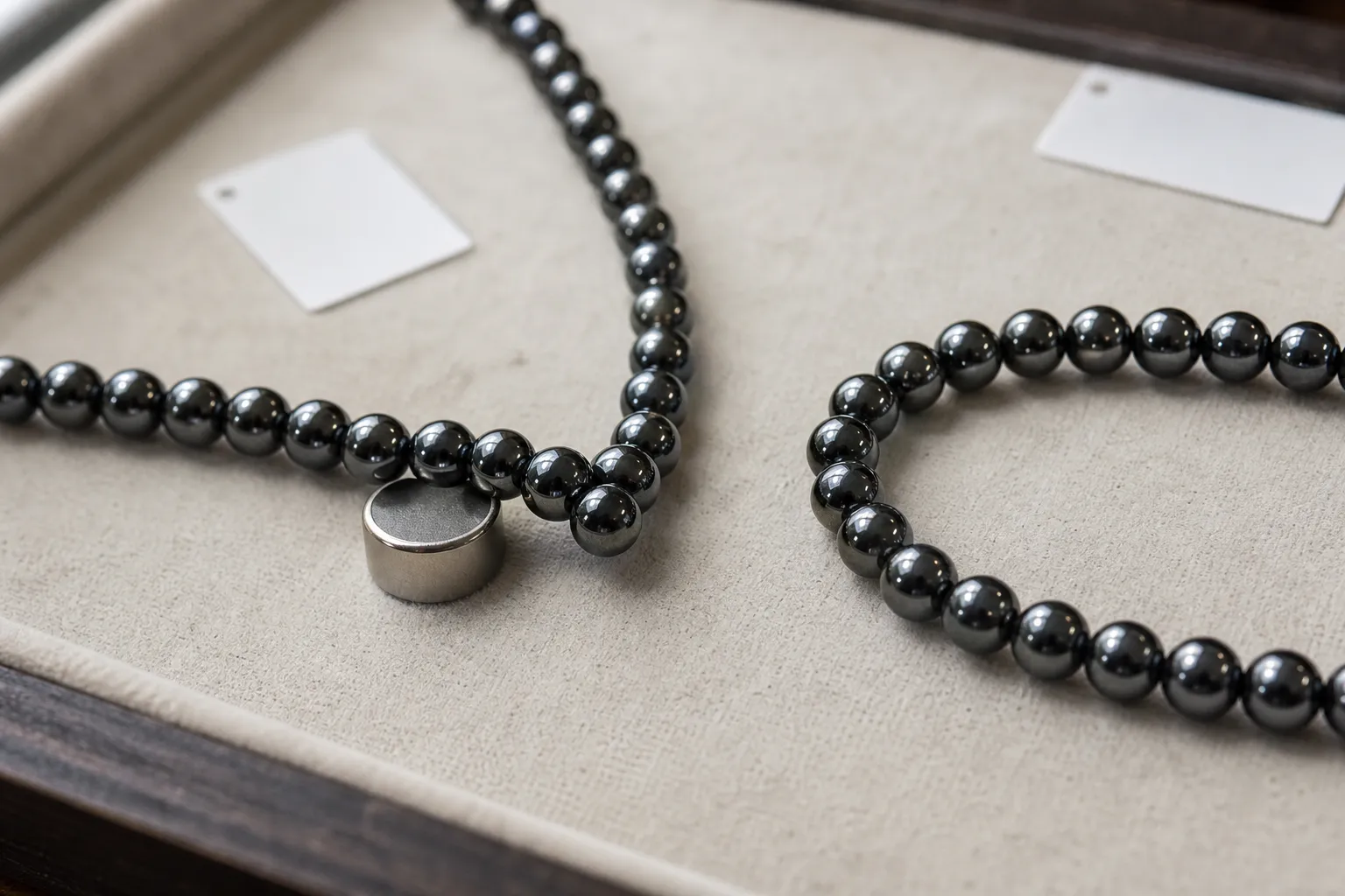 Hematite bead strands being compared with a small magnet to show different magnet responses