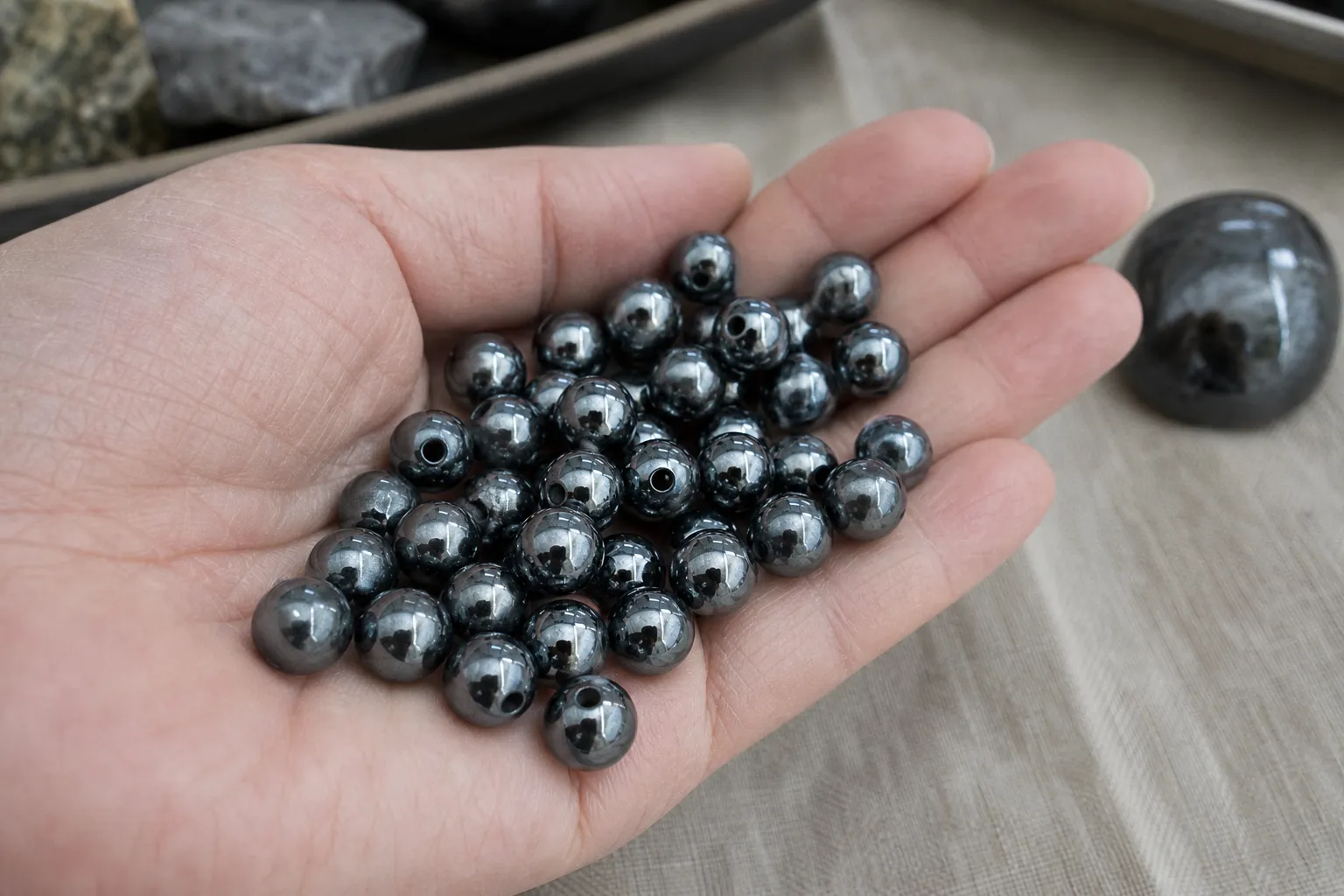 Polished hematite beads with a dark metallic surface shown as objects that can feel weighty in the hand